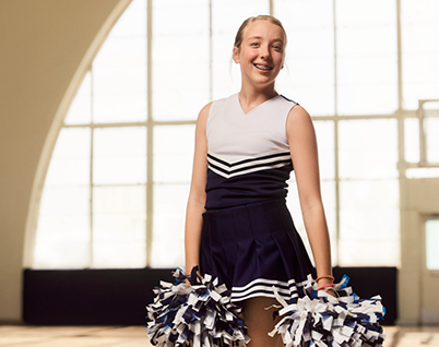 Anna, a 12 year old eczema patient, smiles in her cheerleading uniform